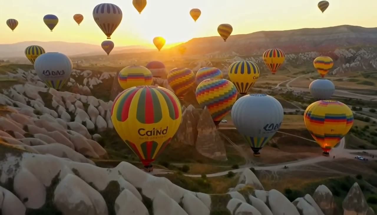 Hot air balloons filling the sky over Cappadocia at sunrise, the camera slowly rising. Still from a video made with MiniMax H3 Max.