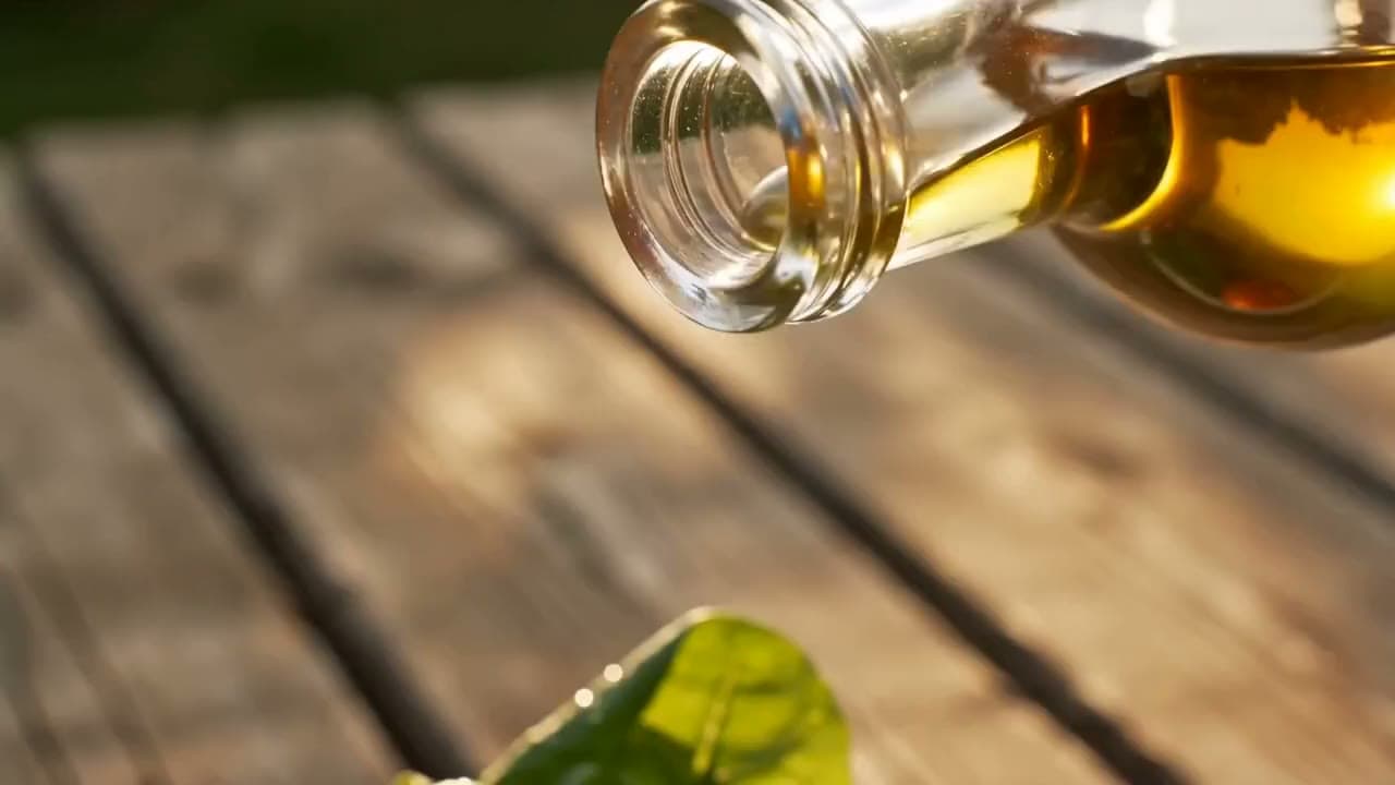 Extra virgin olive oil pouring from the bottle onto a salad, close-up of the stream. Still from a video made with Seedance 2.0.